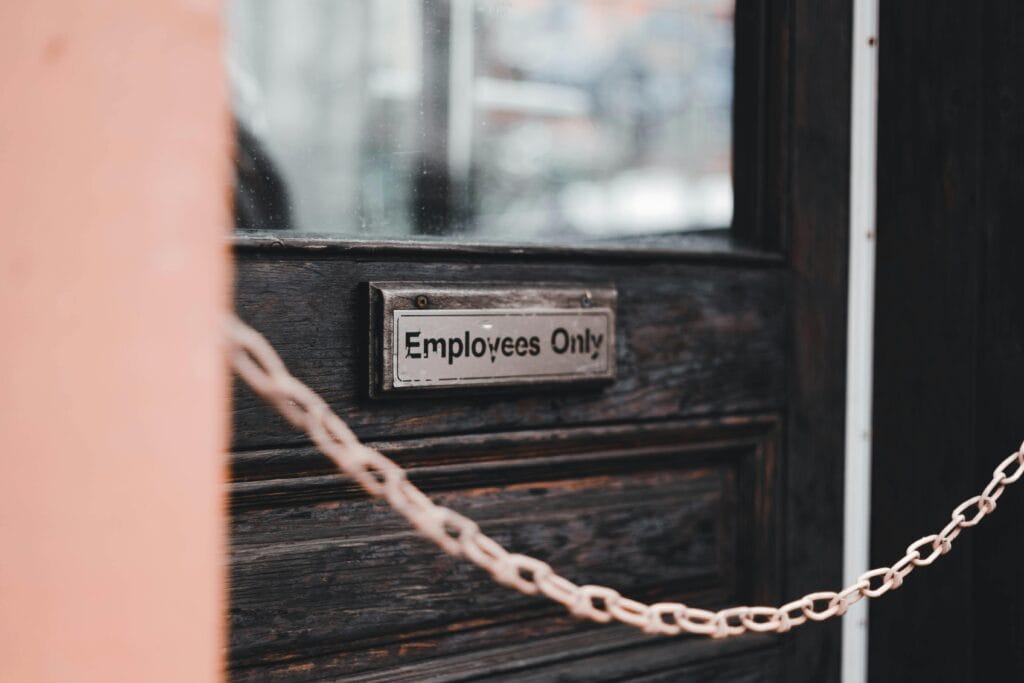 Close-up of an 'Employees Only' sign on a rustic wooden door secured by a chain.