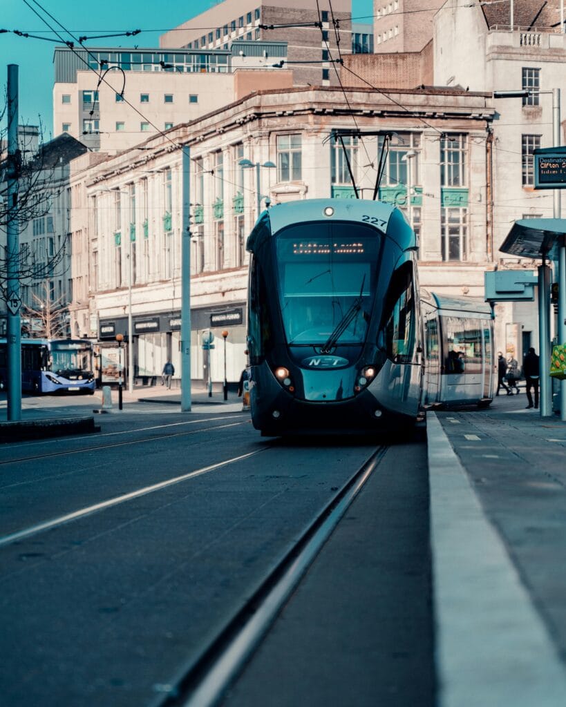 A sleek tram travels through Nottingham city center, showcasing urban public transportation in England.
