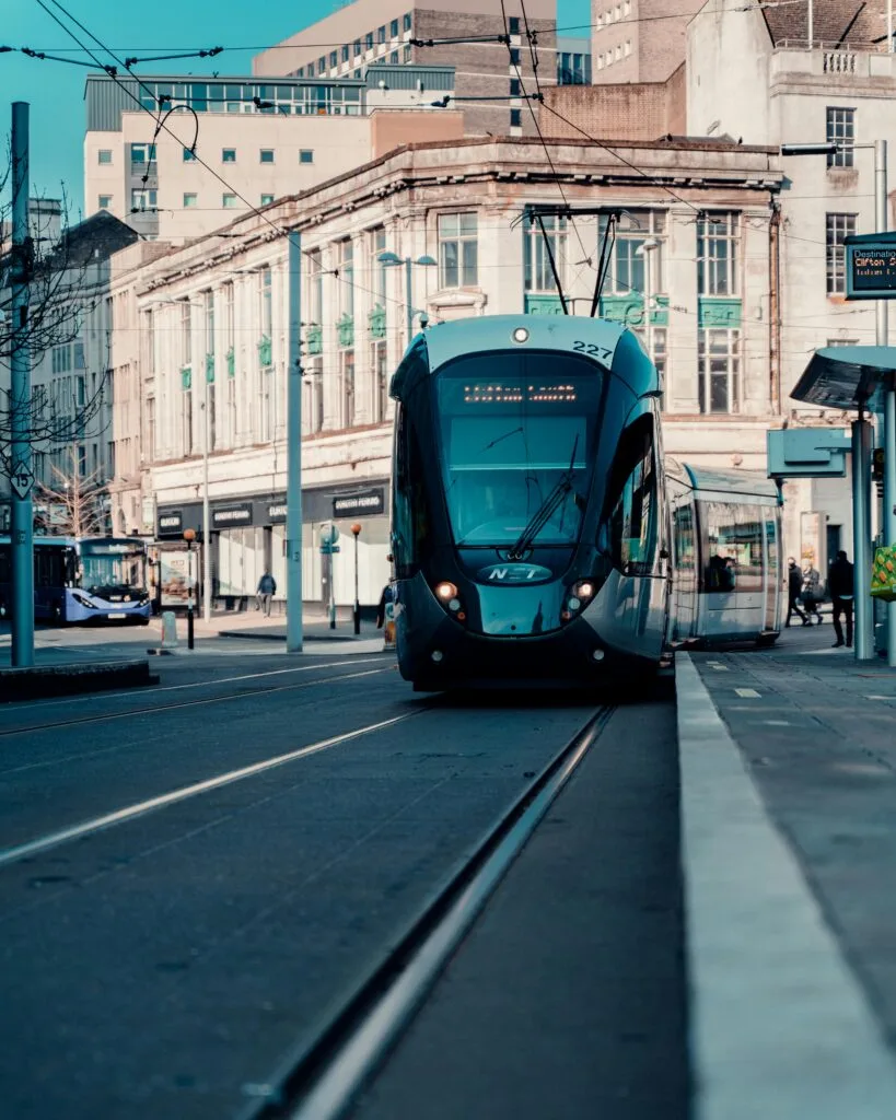 A sleek tram travels through Nottingham city center, showcasing urban public transportation in England.